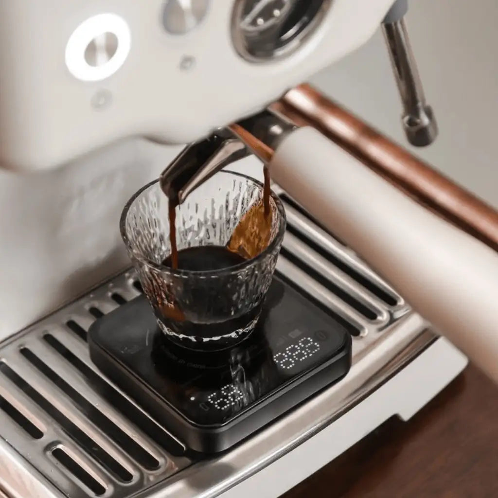 Aktionsbild der BOOKOO THEMIS Mini, steht auf Espressomaschine, die grade einen Espresso Shot ausführt