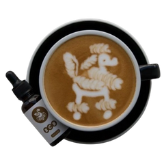 Tasse von oben mit Latte Art von einem Pudel, daneben die BCB Tropfen
